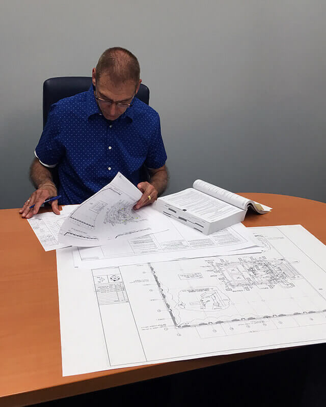 Three engineers sitting together at a desk and planning over an engineering diagram.