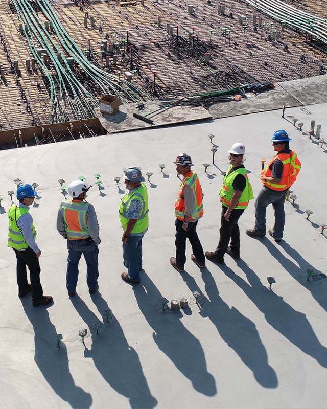 A group of engineers wearing safety gear while standing at a constrution site.