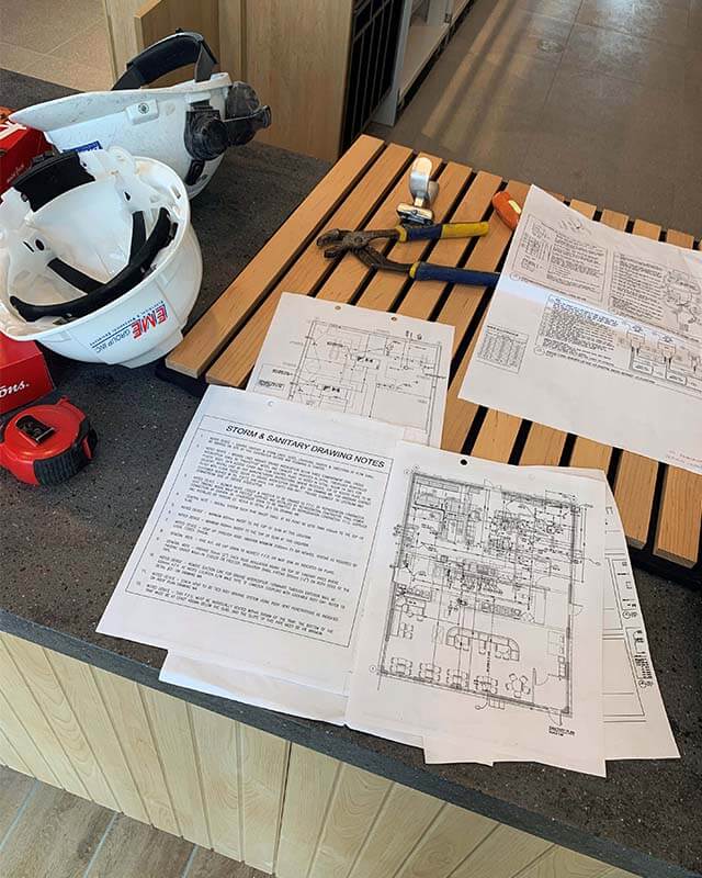 Engineering diagrams, tools, and safety equipment sitting on a counter top.